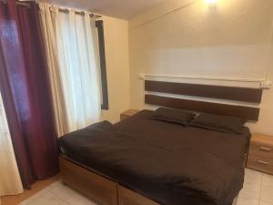 a bedroom with a bed with a headboard and curtains at Peaceful Pines Cottage in Bhowāli
