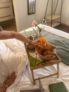 a person reaching for a tray of pastries on a bed at Hôtel Abalone - Centre Gare in Nîmes