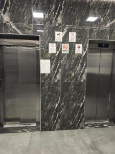 an elevator in a building with signs on the wall at Red School Central Apartment New Bazaar in Tirana