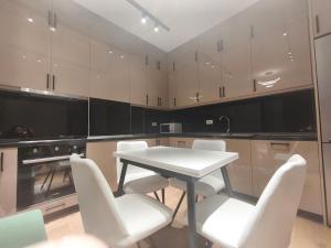 a kitchen with a white table and white chairs at Red School Central Apartment New Bazaar in Tirana