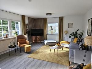 a living room with a couch and chairs and a tv at Landhaus SoonZauber - Exklusives Paar-Hideaway im Naturpark Soonwald-Nahe in Münchwald