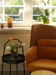 a living room with a chair and a table with flowers at Landhaus SoonZauber - Exklusives Paar-Hideaway im Naturpark Soonwald-Nahe in Münchwald