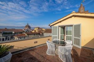 a balcony with white chairs and a table on a building at Hotel Patria in Pistoia