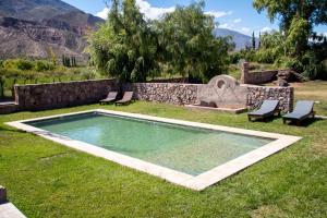 a swimming pool in the grass with two chairs and a fountain at Villa Laureana in Huacalera