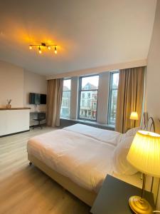 a bedroom with a large white bed and windows at Hotel La Noire - Delft City Centre in Delft