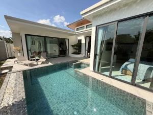 a swimming pool in front of a house at Chareen Pool Villa in Ban Khlong Haeng