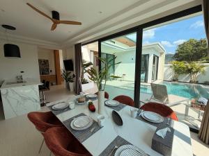 a dining room with a table and chairs and a pool at Chareen Pool Villa in Ban Khlong Haeng