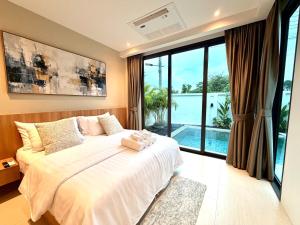a bedroom with a large bed and a large window at Chareen Pool Villa in Ban Khlong Haeng