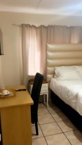a hotel room with a bed and a desk and a chair at Tesco Accommodation in Gqeberha