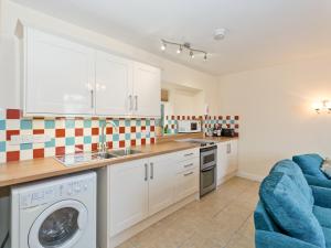a kitchen with white cabinets and a washing machine at Tinakori in Staithes
