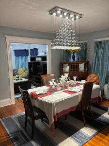 a dining room with a table with chairs and a chandelier at Eden's Lodge in East Hartford