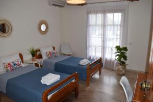 a bedroom with two beds and a table and a window at Tolo Blue Bay in Tolo