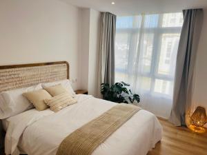 a bedroom with a white bed with a large window at RÍA LIVING - Calma 02 in Cee