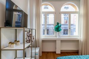a room with three windows and a table with a tv at Realkasa Kairos Luxury Apartments in Bologna