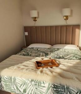 a bed with a tray with two wine glasses on it at Apartamenty PETRA Supraśl in Supraśl