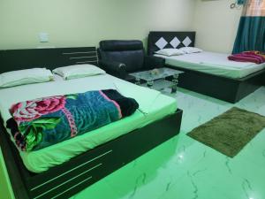 a bedroom with two beds and a couch at Paromita inn in Tajpur +3 photos