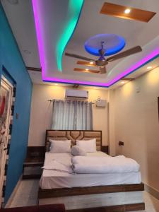 a bedroom with a bed with a purple and green lighting at Paromita inn in Tajpur