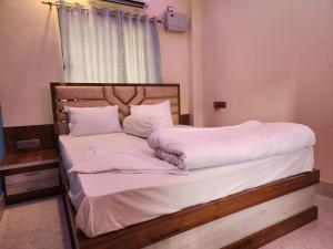 a bed with white sheets and pillows in a room at Paromita inn in Tajpur