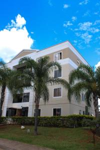 a white building with palm trees in front of it at Diamante em Brasília in Brasília