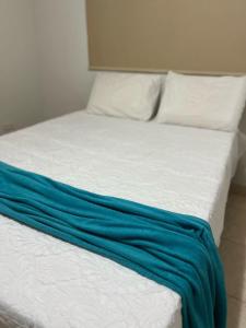 a bed with a blue blanket on top of it at Casa AGV 77 - Gaibu Beach in Cabo de Santo Agostinho