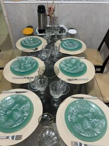 a table with green and white plates and wine glasses at Casa AGV 77 - Gaibu Beach in Cabo de Santo Agostinho +5 photos
