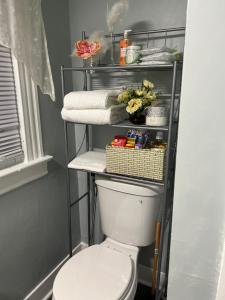 a bathroom with a toilet and a shelf with towels at Eden's Lodge in East Hartford