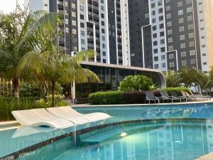 a swimming pool with white chairs and buildings at Elevé Gamuda in Banting +48 photos