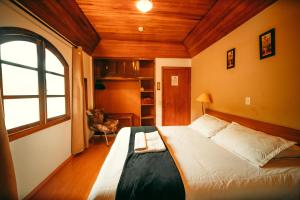 a bedroom with a bed in a room with a window at Hotel Geneve - 2km do Capivari in Campos do Jordão