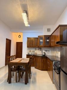 a kitchen with wooden cabinets and a table with chairs at 2BR luxury Apartment in Mount Lavinia - Benetia Stay in Mount Lavinia