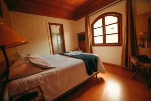 a bedroom with a bed in a room with a window at Hotel Geneve - 2km do Capivari in Campos do Jordão