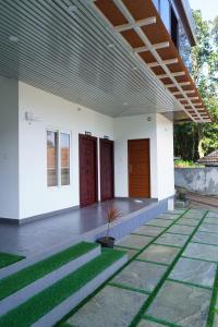 a building with two red doors and green grass at Mountain Mist Ranipuram in Kallar