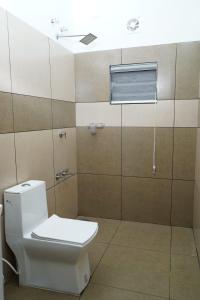 a bathroom with a white toilet and a window at Mountain Mist Ranipuram in Kallar