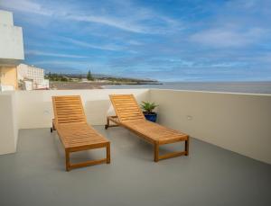 two wooden chairs sitting on a balcony overlooking the ocean at The Lookout | Private Beach Access in São Roque