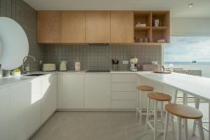 a kitchen with white cabinets and a counter with stools at The Lookout | Private Beach Access in São Roque