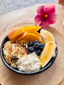 a plate of food with fruit and yogurt and a flower at Cabañas Alondra - Hotel Boutique in Vergara