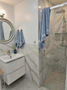 a bathroom with a shower and a sink and a mirror at Apartamenty PETRA Supraśl in Supraśl