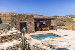 a stone house with a swimming pool in a yard at Marilias cycladic home in Agios Fokas