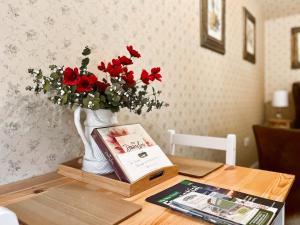 a table with a vase with red flowers and a book at Cottage 1 - Uk46611 in Broughton