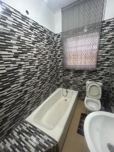 a bathroom with a tub and a toilet and a sink at Macdel Guesthouse And Condos in Kumasi