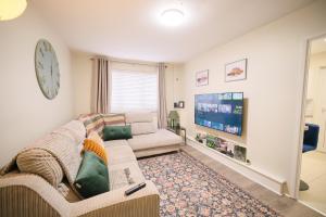 a living room with a couch and a clock on the wall at 1 Bedroom Apartment By Travel Lets Holiday Homes Derry Beside The City Walls in Derry Londonderry