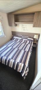 a bed with a blue and white striped comforter in a room at BILOT Caravan in Heysham