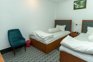 a room with two beds and a blue chair at Hotel Tawhid in Rangpur