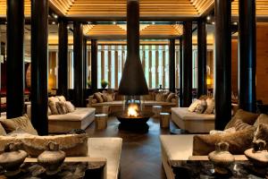 a living room with couches and a fire in the middle at The Chedi Andermatt in Andermatt