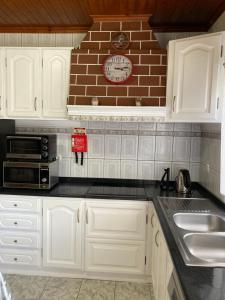 a kitchen with white cabinets and a clock on the wall at Casa da Baía da Manhenha in Manhenha
