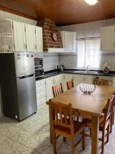 a kitchen with a wooden table and a refrigerator at Casa da Baía da Manhenha in Manhenha