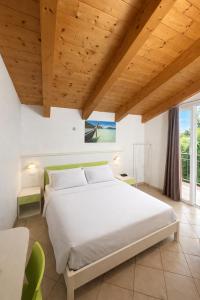 ein Schlafzimmer mit einem großen weißen Bett und Holzdecken in der Unterkunft Hotel Sasselli Dipendenza Hotel Zamagna in Cesenatico + 55 Fotos