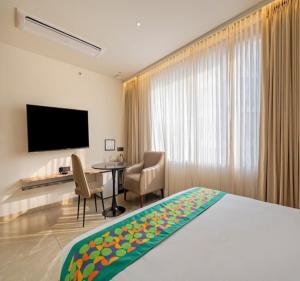 a hotel room with a bed and a desk and a television at The Kalvin Plaza in New Delhi