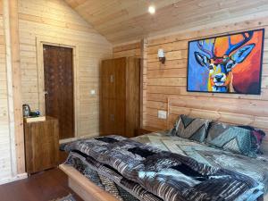 a bedroom with a bed with a painting on the wall at Samlaun Chalet and Retreat in Kanatal