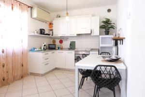 a kitchen with white cabinets and a table and chairs at Casa Segantini - Relax Apartment 2 in Arco