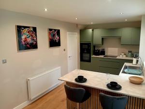 a kitchen with green cabinets and a counter with chairs at Martindale Close - 3 Bedrooms - Sleeps 5 in Whitehaven